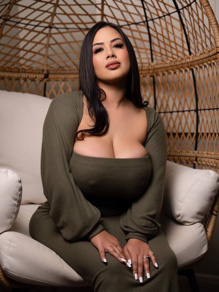 Portrait of Alivia sitting in a rattan egg chair with her hands resting on her knees